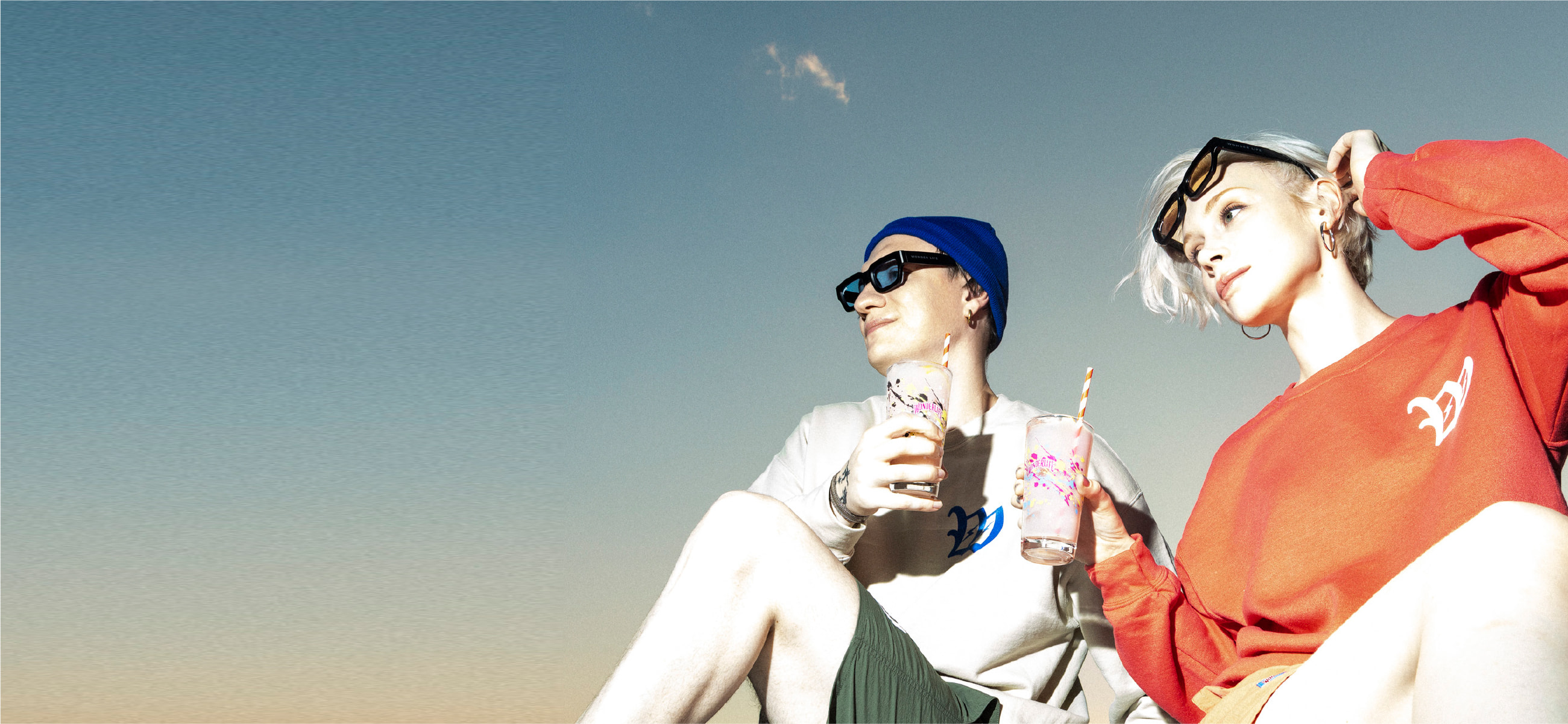 屋外でドリンクを持ちながら座る二人の人物の写真