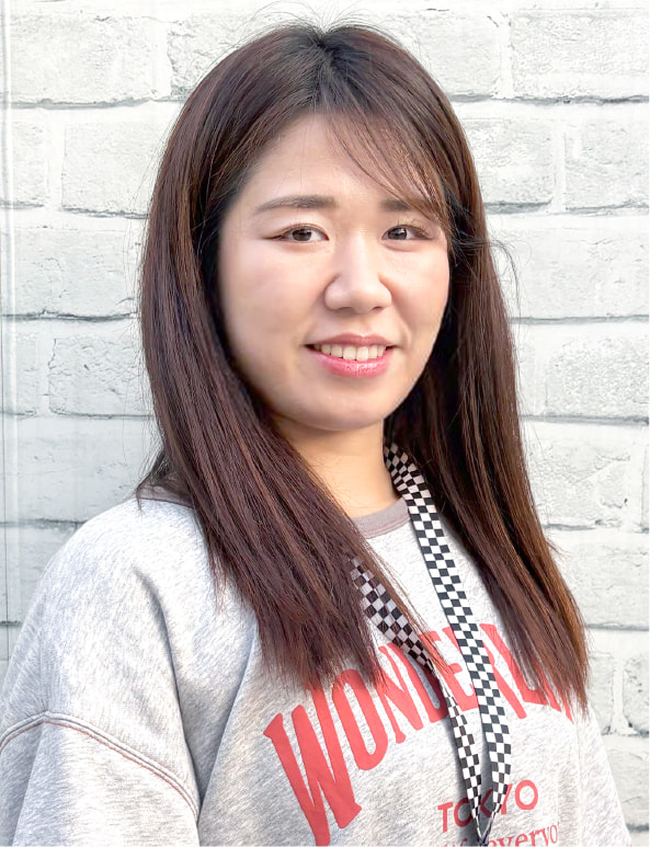 白い背景の前で笑顔を見せる女性トレーナーのポートレート写真