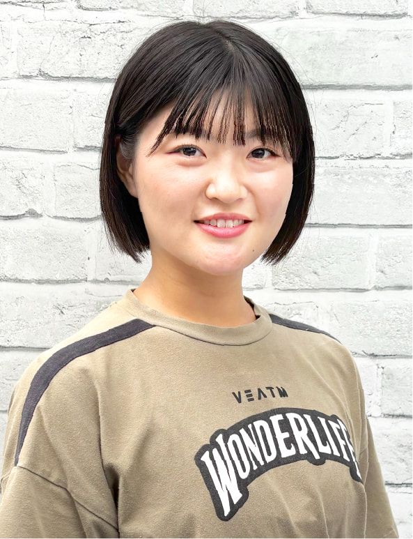 白い背景の前で笑顔を見せる女性トレーナーのポートレート写真