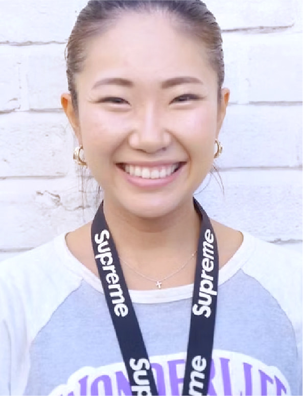 白い背景の前で笑顔を見せる女性トレーナーのポートレート写真